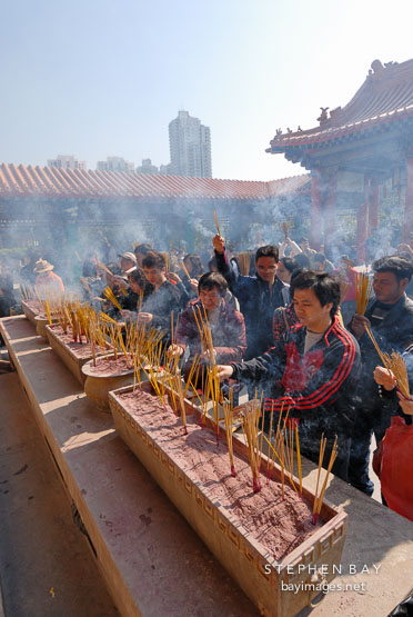 Lighting incense to honor their ancestors. Wong Tai Sin Temple, Hong Kong, China.