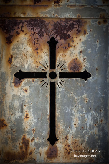 Rusted iron cross window slits. Pere Lachaise Cemetery, Paris, France.