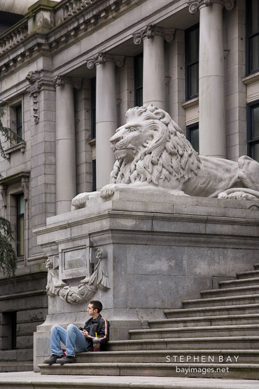 Young man sitting on the steps of the Vancouver Art Gallery. Vancouver, Canada.