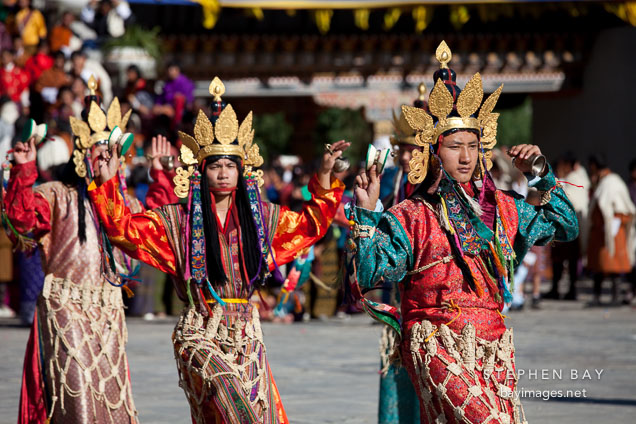 Dancers with long brocade dresses and carved bone ornaments. Thimphu tsechu, Bhutan.