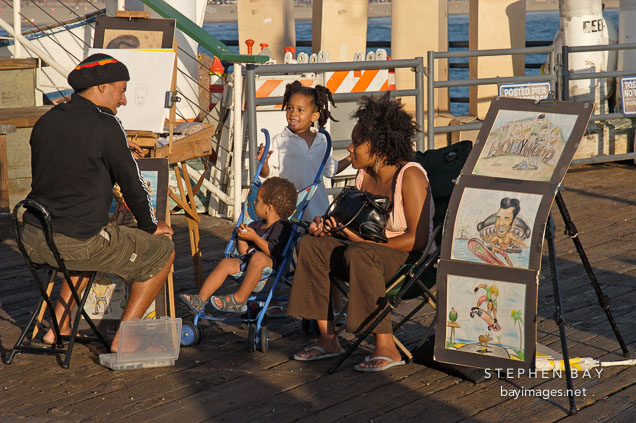 Artist drawing a family portrait. Santa Monica Pier, California, USA.