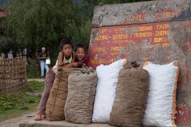 Boys standing by direction sign. Nobding, Bhutan.