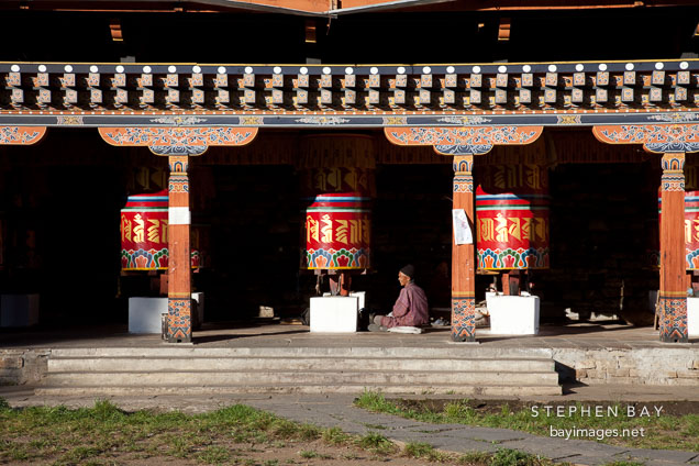 Man sitting by the large prayer wheels at the National Memorial Chorten in Thimphu, Bhutan.