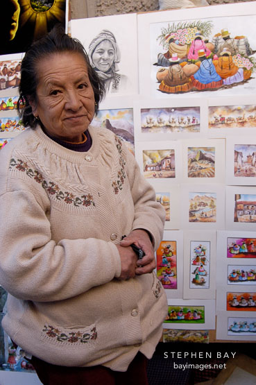 Woman selling prints Pisac market, Sacred Valley, Peru.