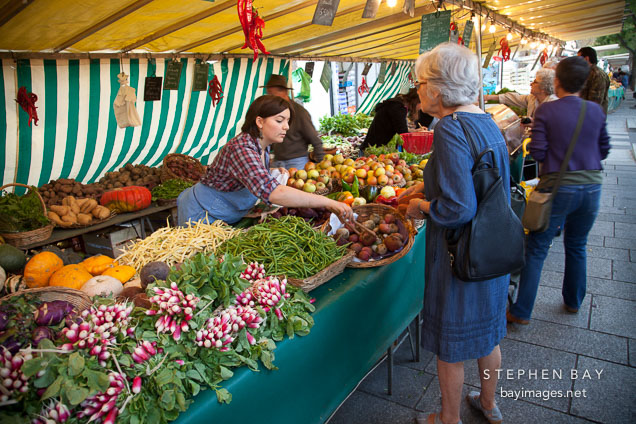 Woman buying rutabagas at the Marche de la Bastille. Paris, France.