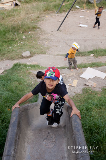 Boy climbing up slide (concrete drain). Thimphu, Bhutan.