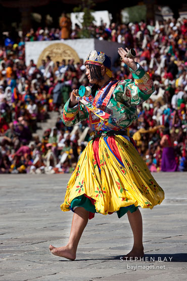 Dancer with knee-length yellow skirt. Thimphu tsechu, Bhutan.