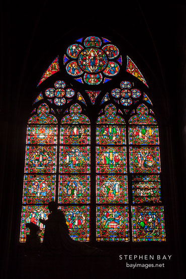 Praying statue and stained glass. Notre Dame Cathedral, Paris.