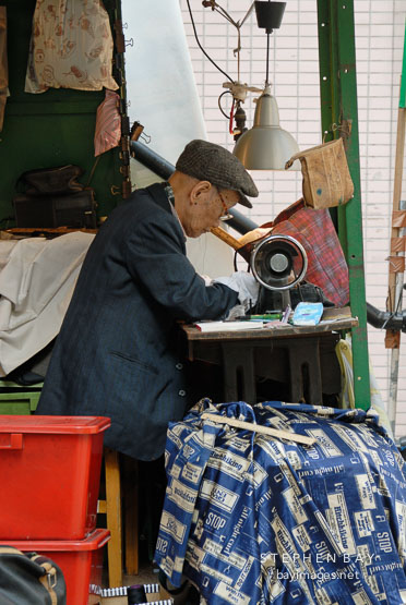 Tailor working on his sewing machine. Pottinger street, Hong Kong, China.