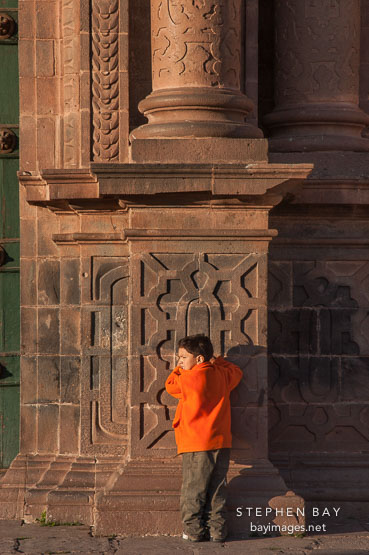 Boy in orange jacket. The Cathedral, Plaza de Armas, Cusco, Peru.