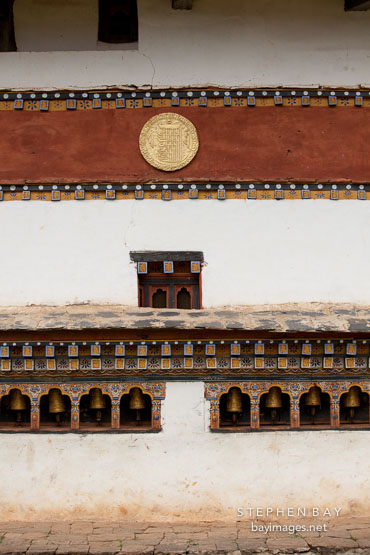 The outer walls of Chimi Lhakhang are lined with prayer wheels. Lobesa Valley, Bhutan.