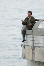 Man fishing with a bare line from railing. Hong Kong, China. - Photo #15276